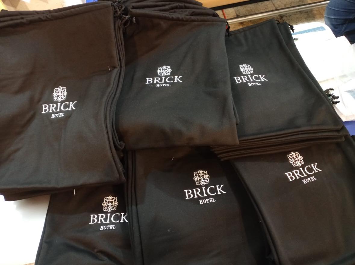 Bolsas promocionales negras de tela estampadas con el logo del Hotel BRICK. Artículos promocionales textiles para hotelería.